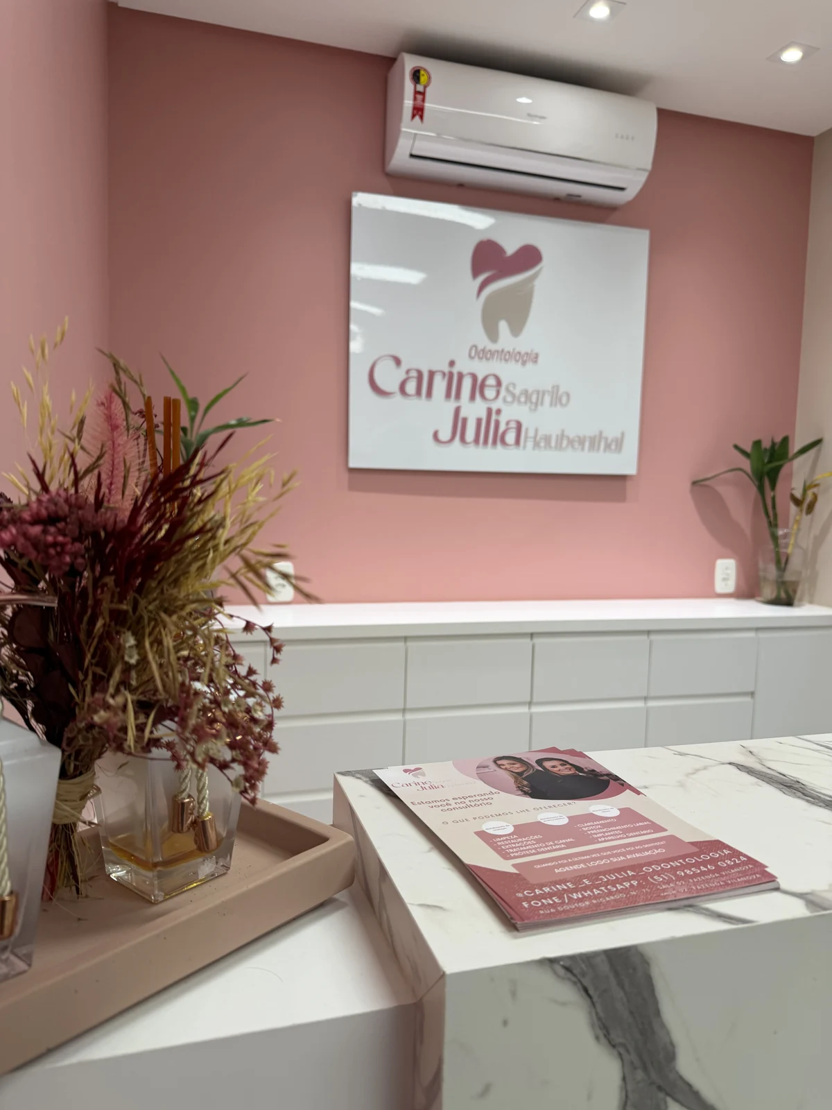 Recepção do consultório com a identificação de Carine Sagrilo e Júlia Haubenthal